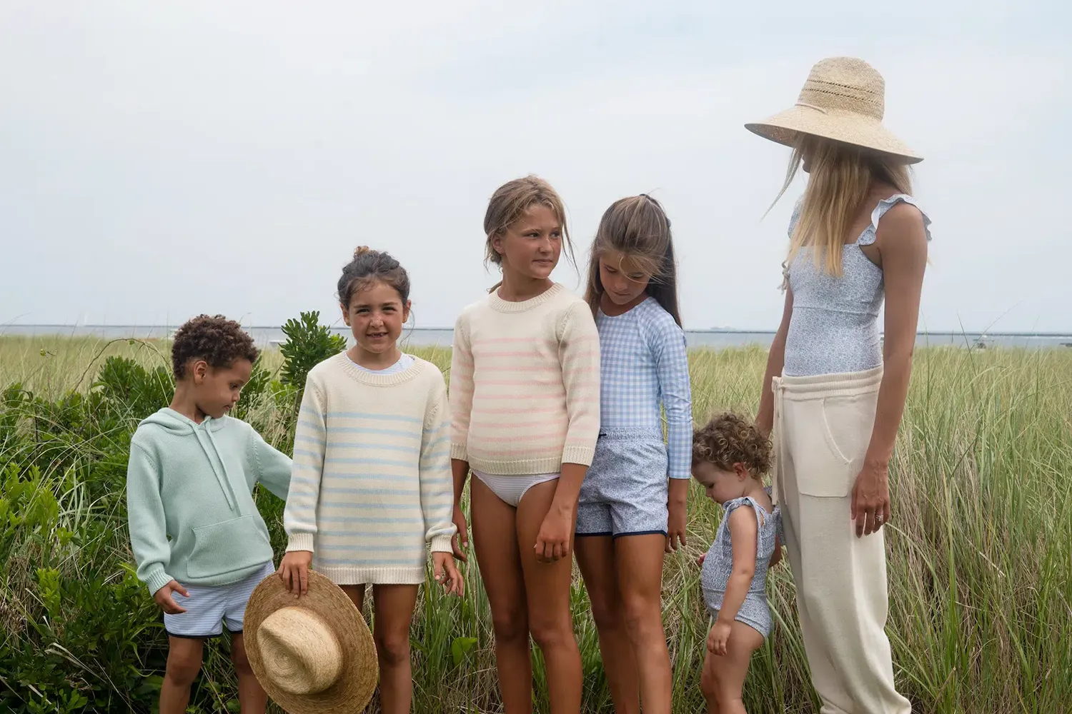Children and a woman in Minnow knitwear standing in a seaside field
