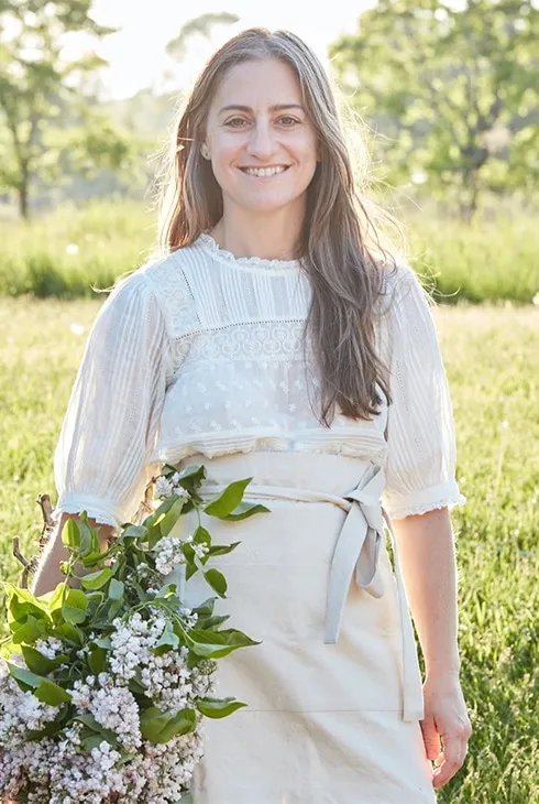 A florist in an apron holding a fresh bouquet in a field