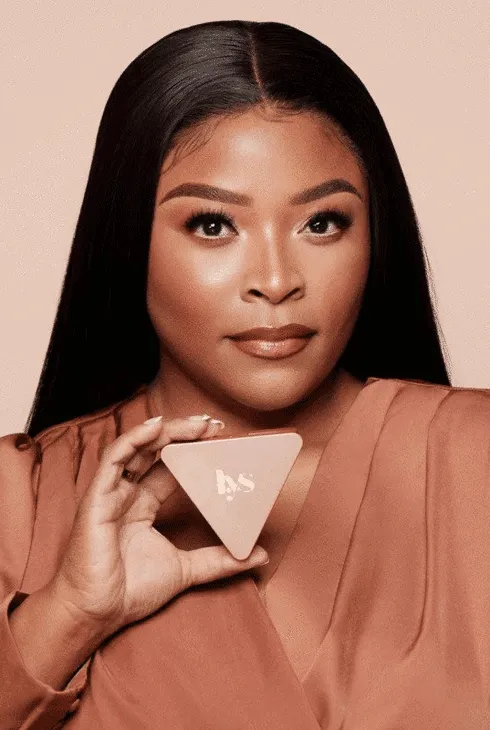 A model holding a triangular LYS Beauty compact beside her face